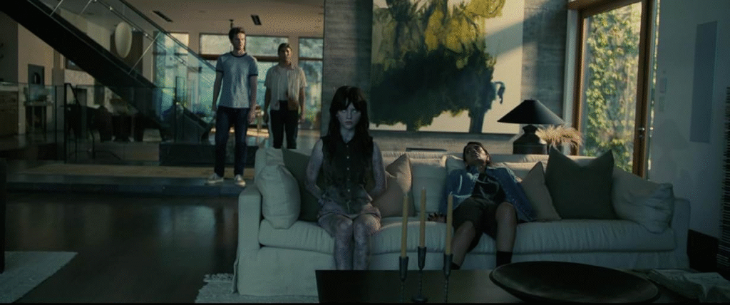 Companion (2025): The AI bot, Iris, and the male lead's female friend, Kat, sitting side-by-side as both are hurt by men.