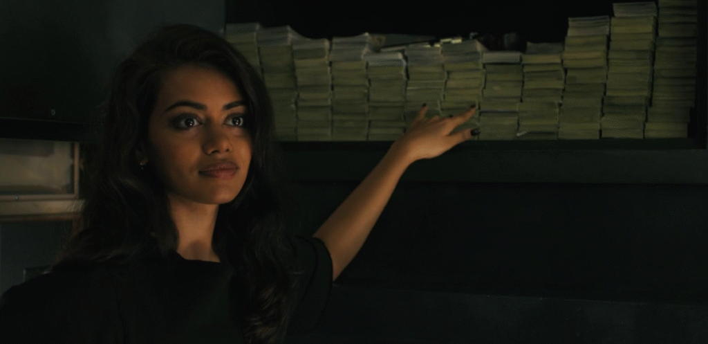 Companion (2025): Characters in the movie trying to steal money. Kat standing in front of stacks of cash.